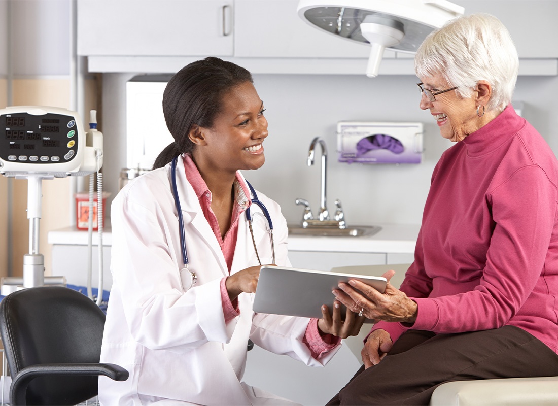 Employee Benefits - Doctor Discussing Records With Senior Female Patient
